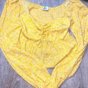 A yellow flower long sleeve. Has a tied ribbon in the middle.